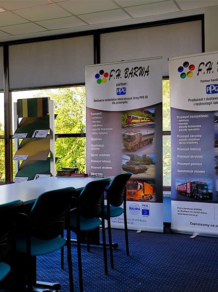 Exhibition of F.P. Barwa advertising banners in conference room. Visible roll-ups presenting company offer, training chairs and tables in background.